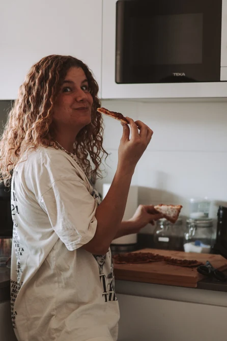 Fabiana en la cocina, probando una porción de pizza casera